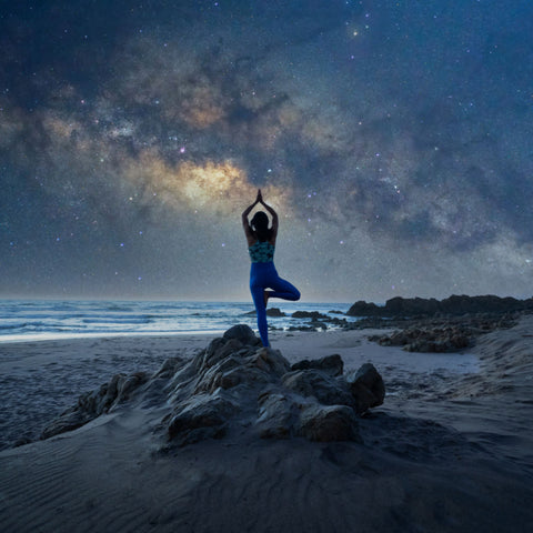 A person practicing yoga at the beach during a starry sky. They are showing why spirituality is important.