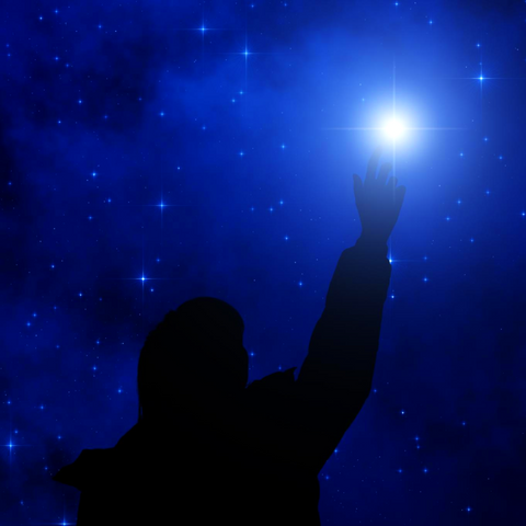 A person reaching for the stars in the night sky, searching for a deeper meaning to spirituality.