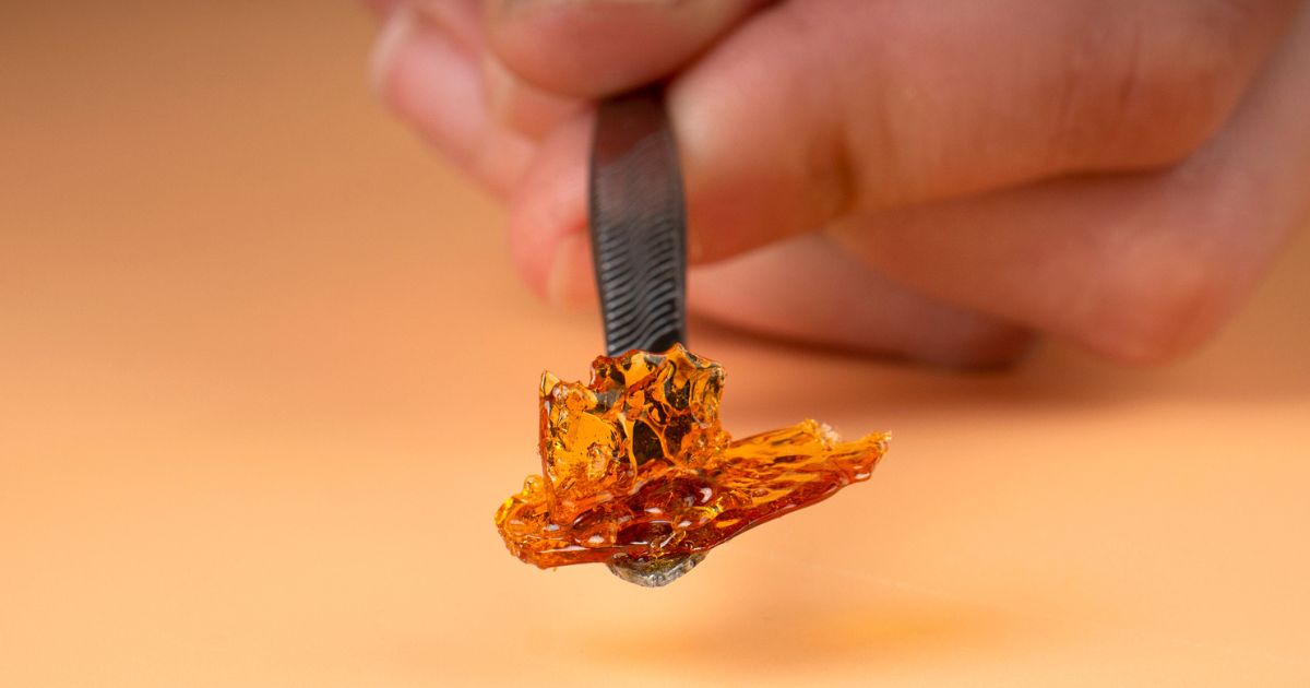 hand holding a dab stick with an orange background