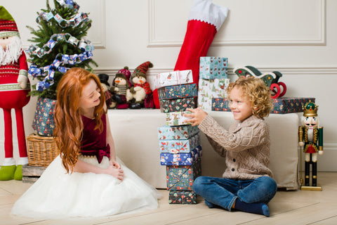 Two children stacking wrapped up gifts into a tower