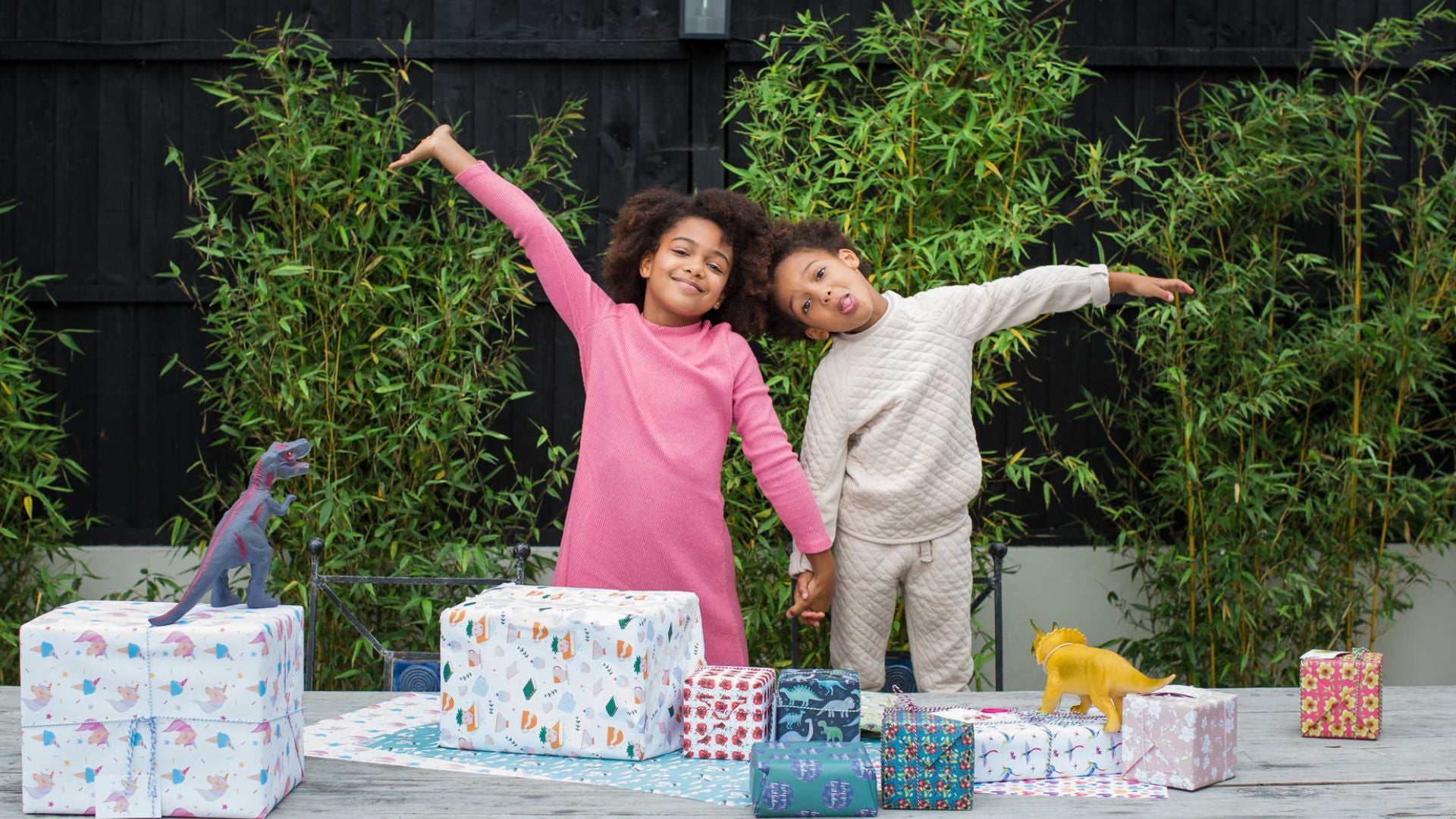 Children standing surrounded by trees and wrapped gifts