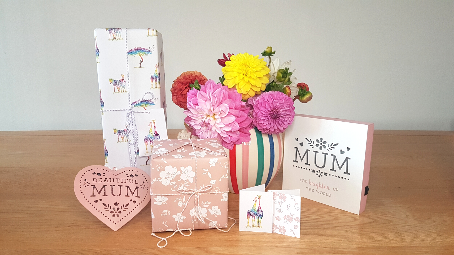 A photo of gifts wrapped in Curlicue sustainable wrapping paper and gift tags for Mother's Day, featuring floral print and safari print