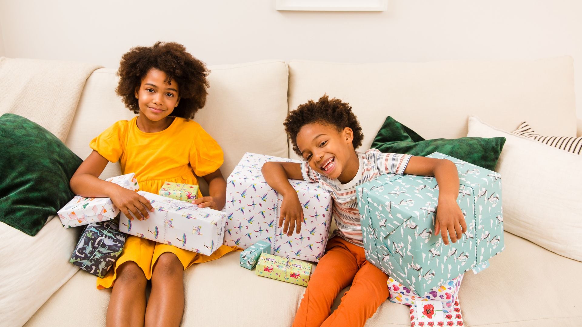 Children sitting on a sofa surrounded by presents wrapped in Curlicue gift wrap