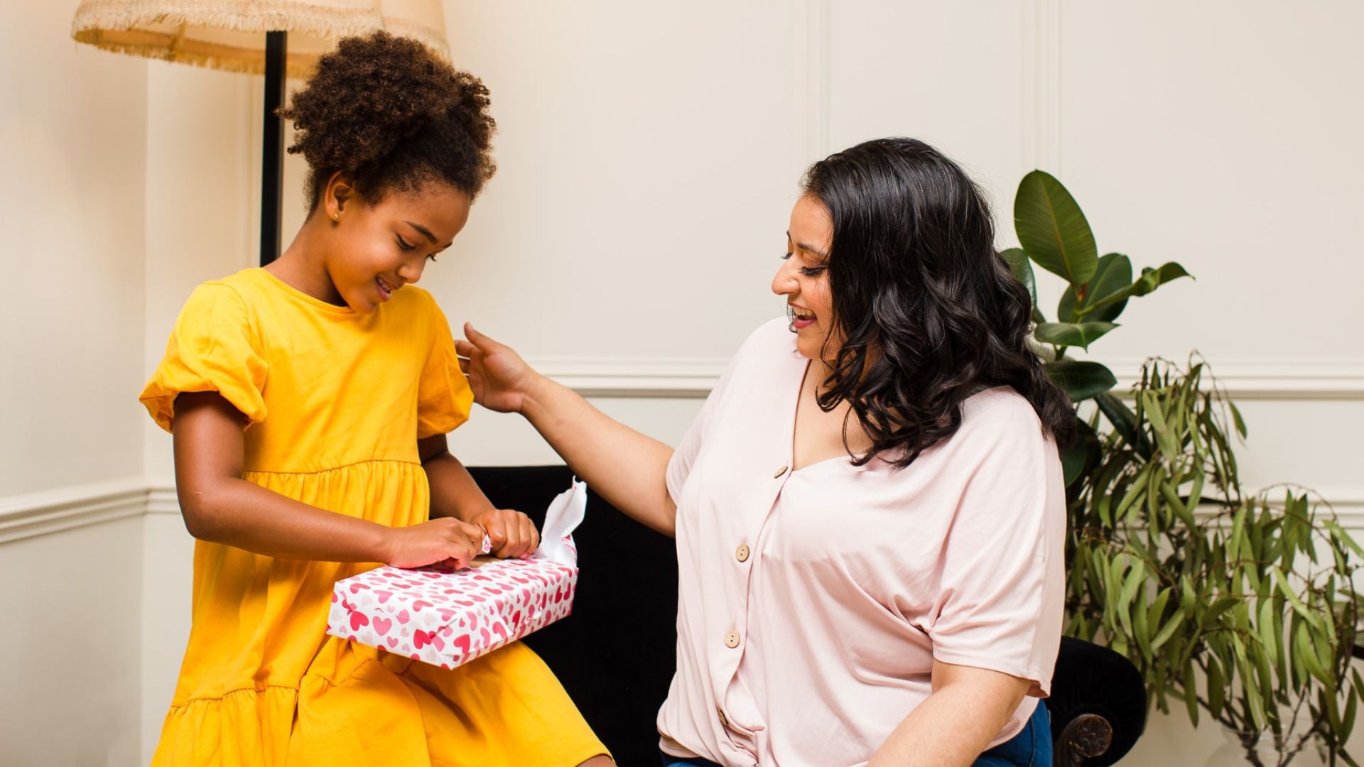 A woman giving a wrapped gift to a child