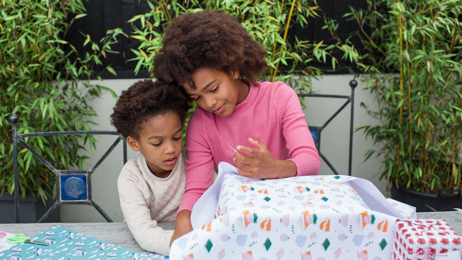 Children wrapping a gift in sustainable Curlicue gift wrap