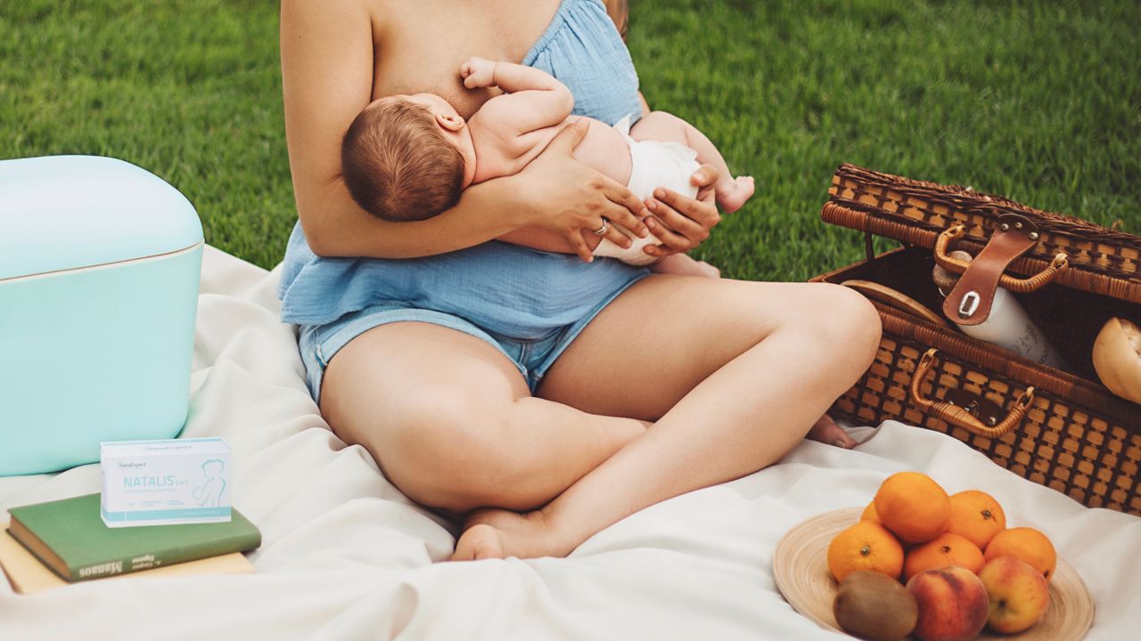 Foto de uma mamã a amamentar o seu bebé sentada na grama