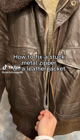 Image of a leather jacket with hand holding the zip