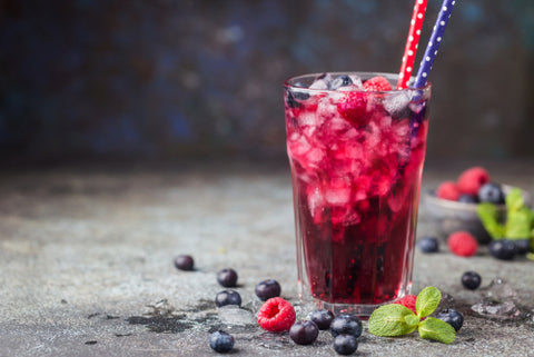 Pink and purple iced tea, garnished with berries and two straws. Find a refreshing and tasty sea moss drink recipe!