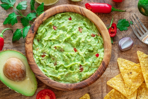 Guacamole, surrounded by the ingredients used to make it. Add sea moss to your guacamole to create an incredibly nourishing snack.