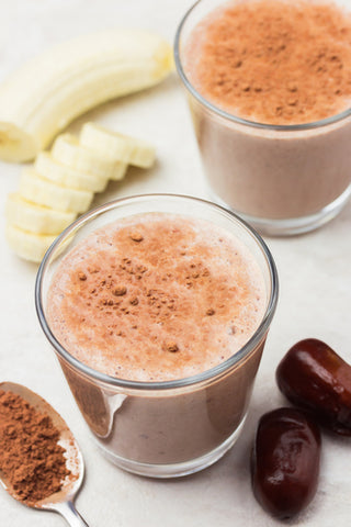 A cocoa shake with bananas and cocoa powder lying next to it. Choose a recipe and make a delicious sea moss smoothie!