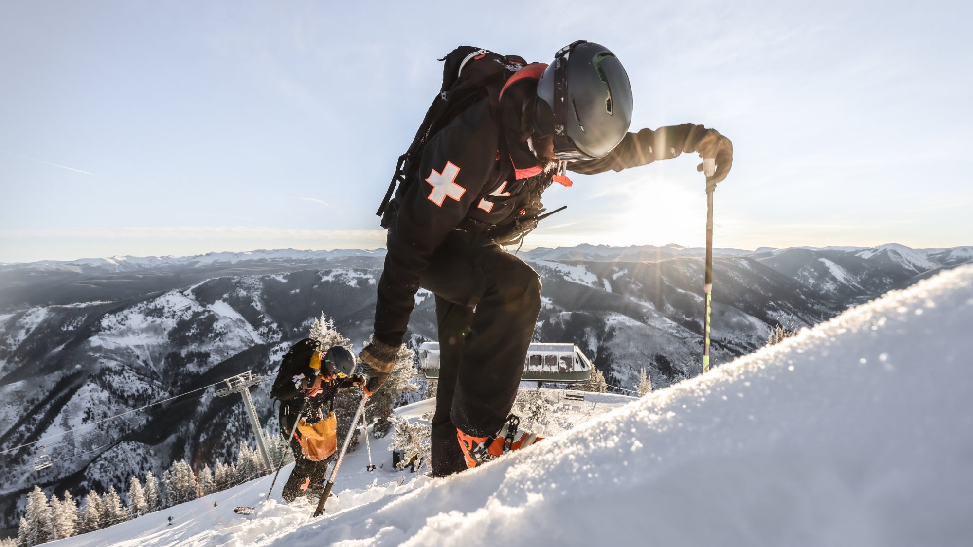 Luke Demuth and another team member boot-pack up a snowy mountain slope