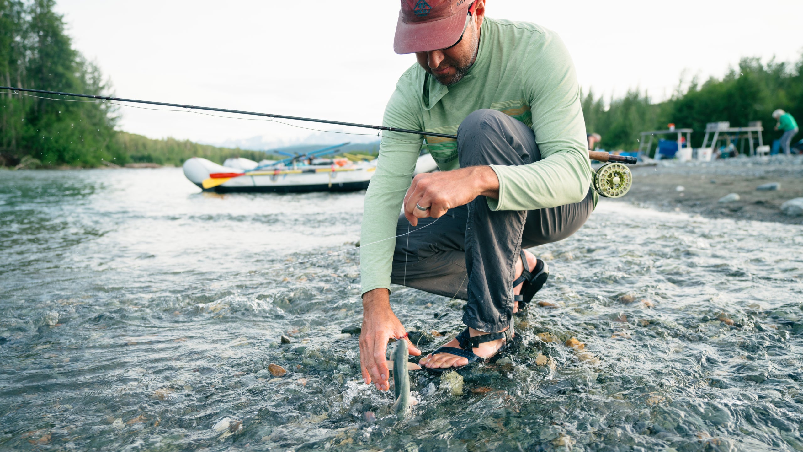 Uncle Tim grabs a small trout he's hooked in a shallow creek.