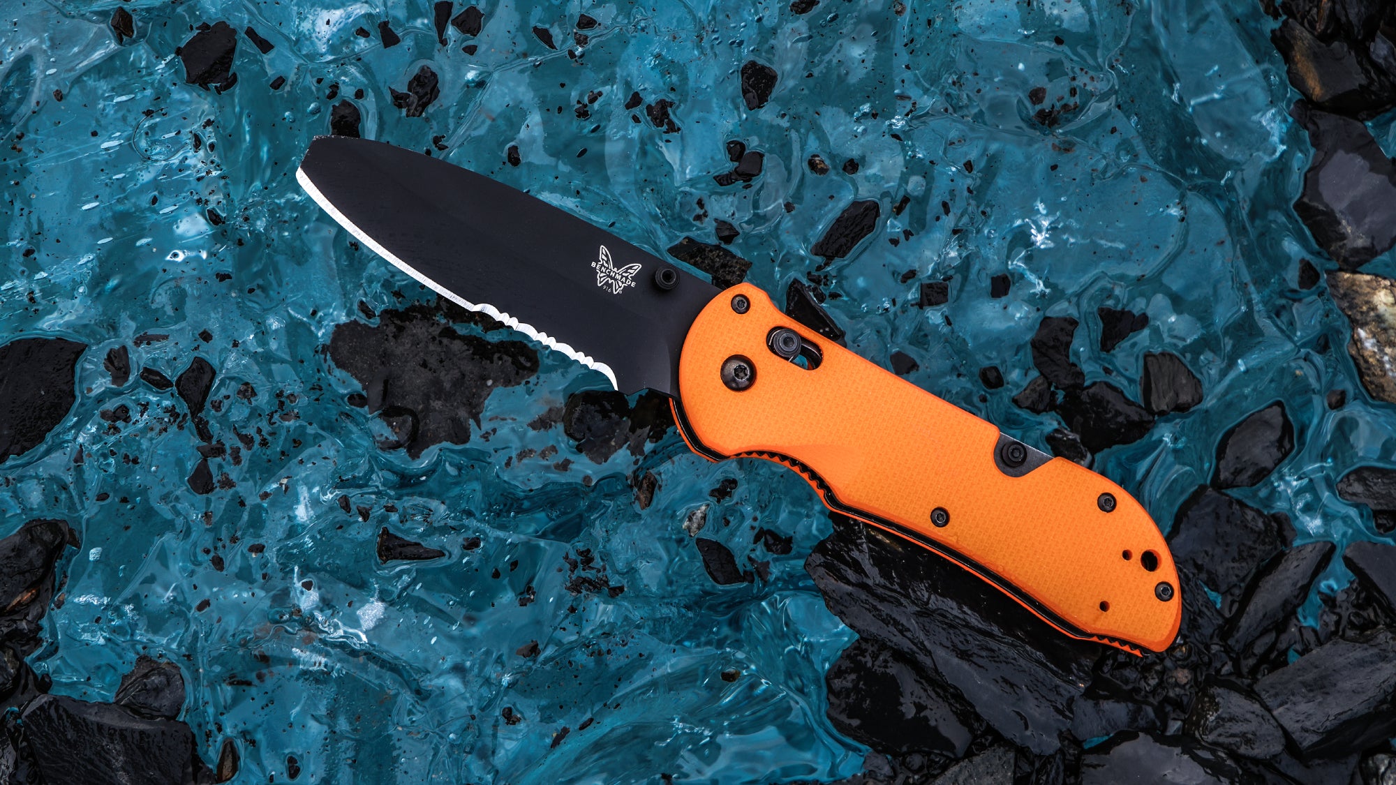 The Benchmade Triage sits on cool blue ice studded with black rock fragments