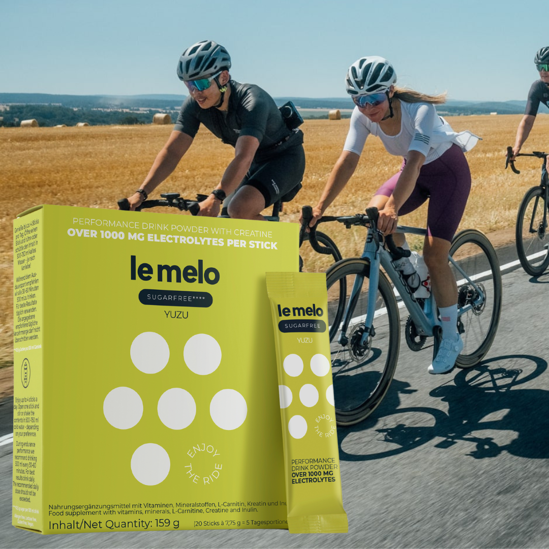 Cyclists riding on a sunny road alongside Le Melo performance drink powder packaging.