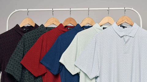 A collection of Kualesa polo shirts in various colors hung neatly on wooden hangers, highlighting eco-conscious apparel options.