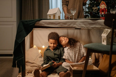 Children read a book in an indoor den at Christmas