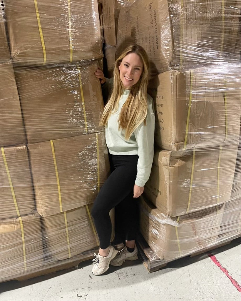 Founder of Keke Jenn Mariani, our Founder standing next to a stack of boxes