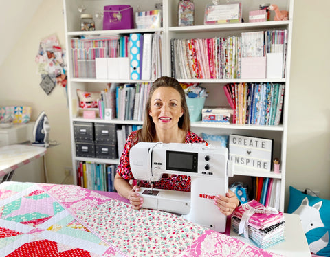 Sarah Ashford sitting in her studio with a sewing machine and quilt 