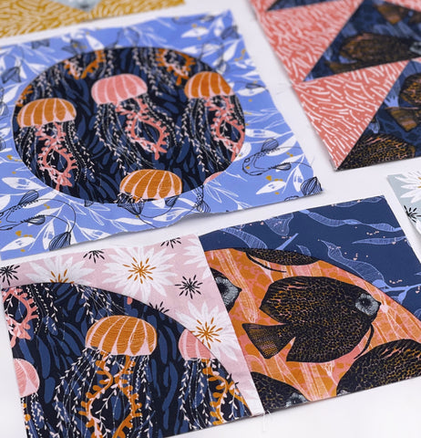 A porthole and drunkards path quilt block featuring jellyfish and a fish