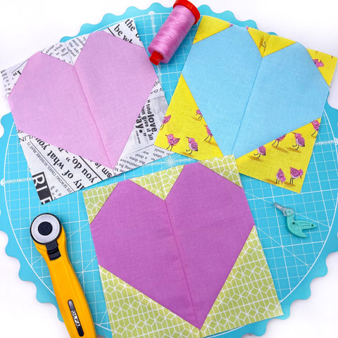 Mini heart blocks in pink, purple and blue on a cutting mat