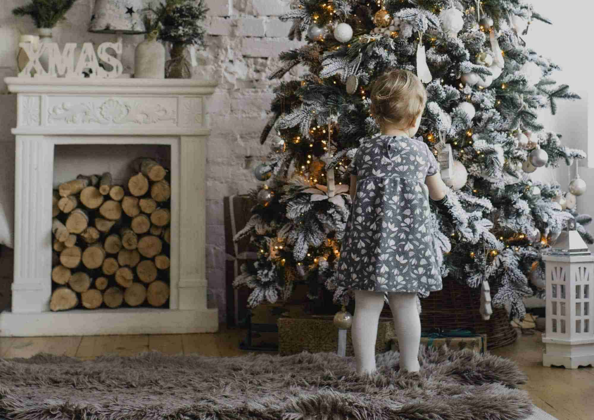 Little Girl in silver dress standing under the Christmas Tree