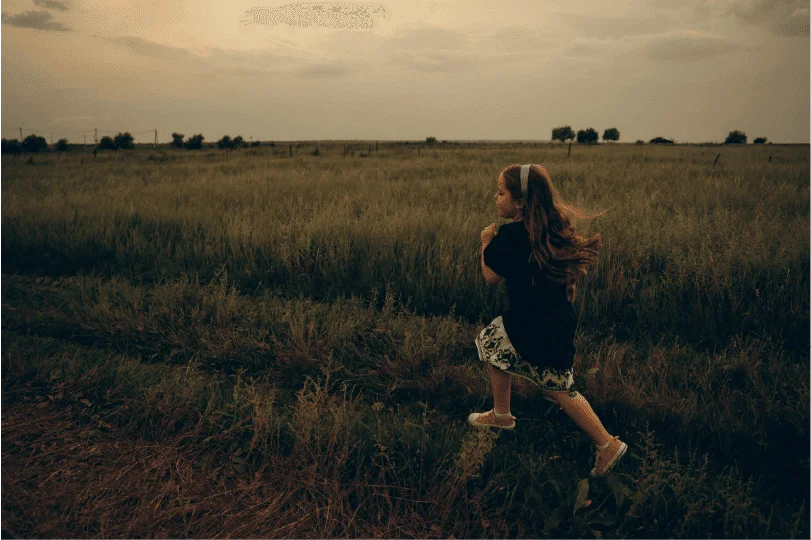 little girl running in sunset field