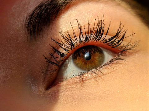 A woman's eye with mascara on the upper and lower lashes.