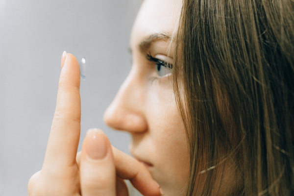 woman holding a contact lens on her finger