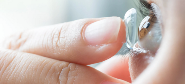 close up of a contact lens on fingertip being inserted into eye