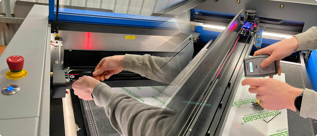 A person conducting maintenance on a laser cutter machine, adjusting its components.