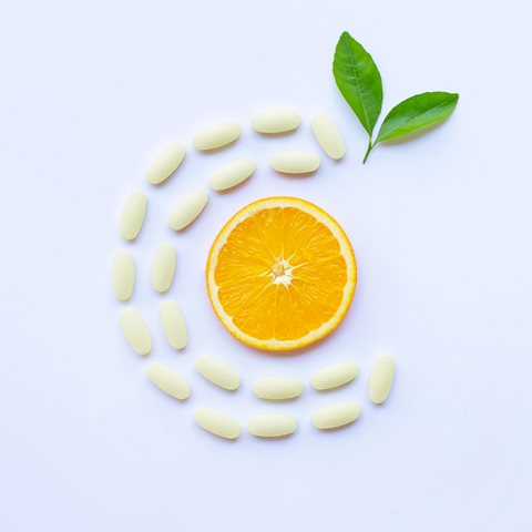 Pills forming the letter C around an orange slice