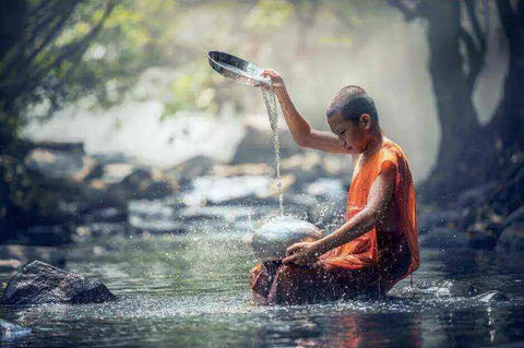 A Buddhist monk performs a water ritual in a stream