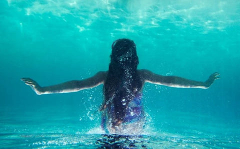 A female Lemurian spreads her arms wide under water