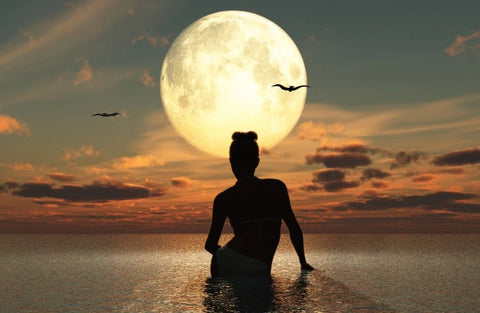 Woman takes a full moon bath in a body of water