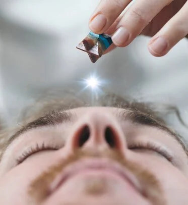 A Merkaba crystal is placed over the Third Eye of a male for spiritual healing