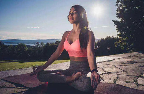 Woman meditates in lotus pose while listening on headphones