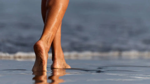 A female walks along the edge of the ocean barefoot