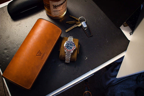 An image showing Luxury Watch Rolls vintage brown leather triple slot watch roll, for three watch storage. The case is closed and one watch pillow is removed, placed outside of the watch roll, with a Rolex GMT Master II Pepsi watch fitted on the watch pillow.