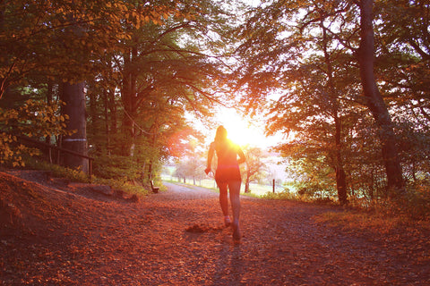 秋の紅葉に染まる山の中をジョギングしている女性