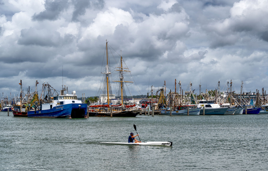 A lonely kayaker paddling in front of fishing trawler in Port Mooloolaba