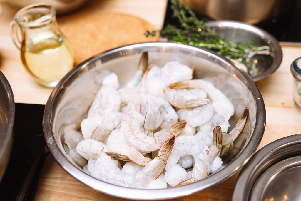 Peeled green prawns in a stainless steel bowl