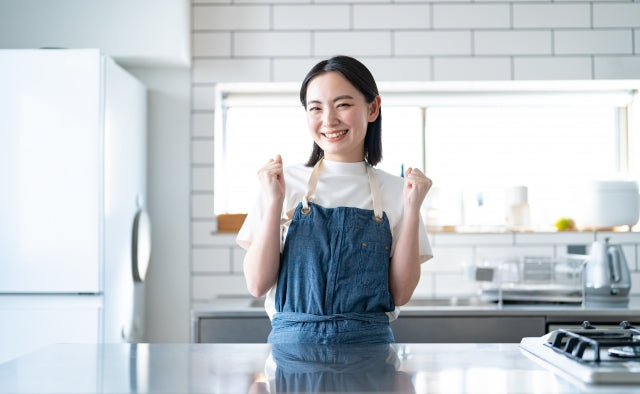 キッチンで嬉しそうにガッツポーズする若い女性