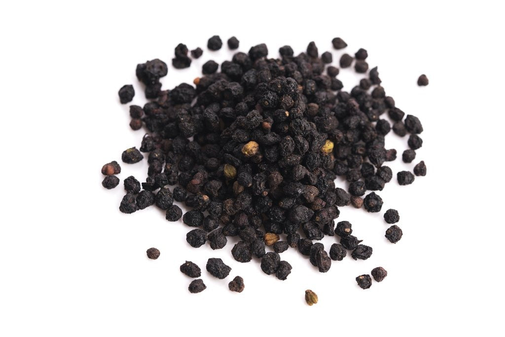 A small pile of dried elderberries on a white table.