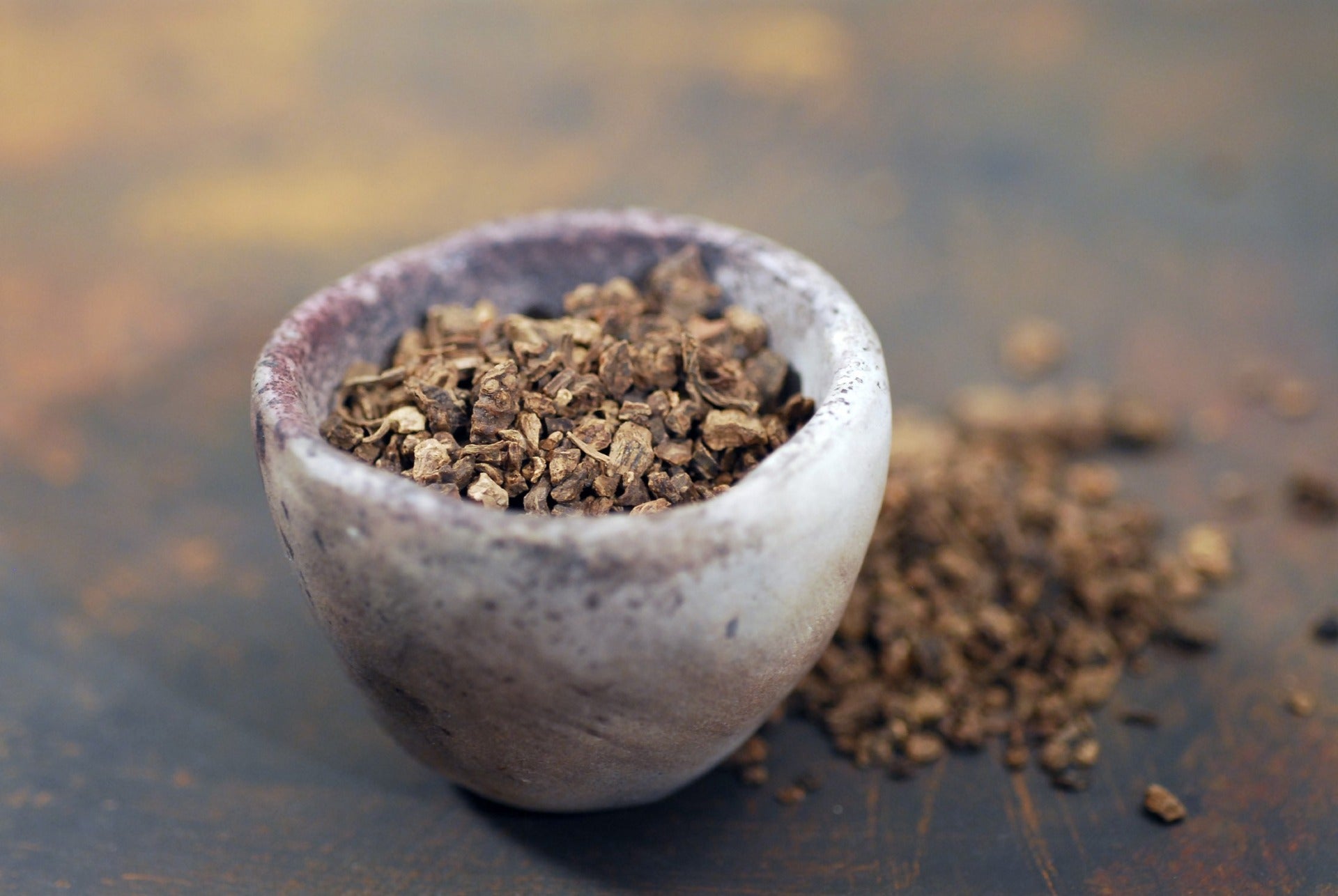 Dried valerian root pieces in a small stone bowl.