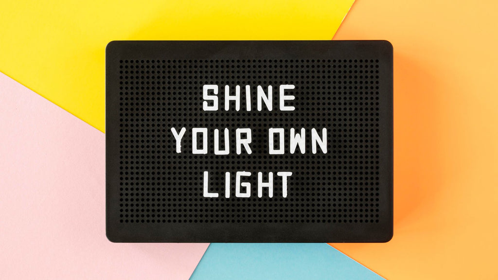 Black letter board with the words, "shine your own light"