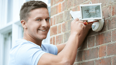 A man installing a security light.