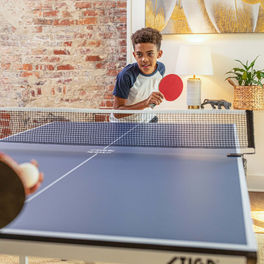 Young boy serving a ping pong ball on a STIGA ping pong table