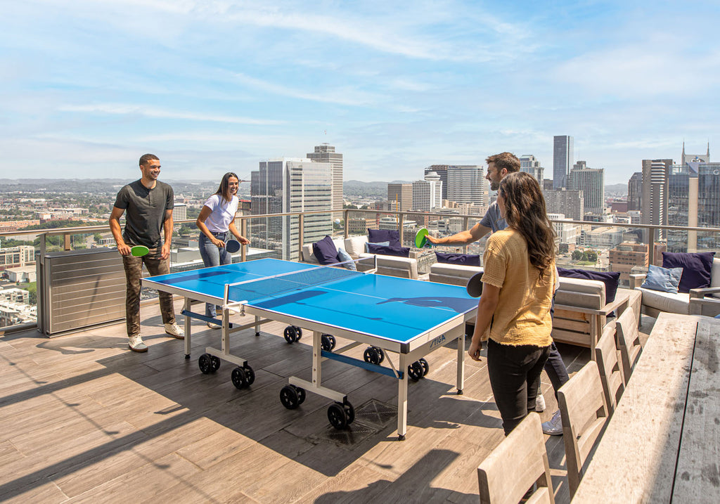 four people playing ping pong outside