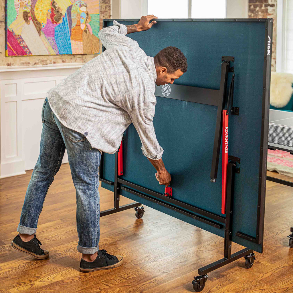 A man folding a STIGA ping pong table into its upright locking position