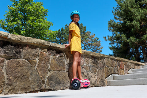 Child preparing to ride GOTRAX Pink Nova LED Hoverboard in the Park